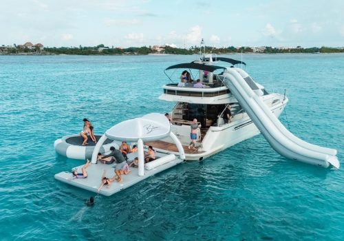 Guests enjoying inflatable water slide and water toys next to the Fairline 65 yacht