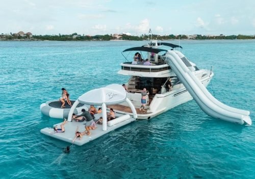 Guests enjoying inflatable water slide and water toys next to the Fairline 65 yacht